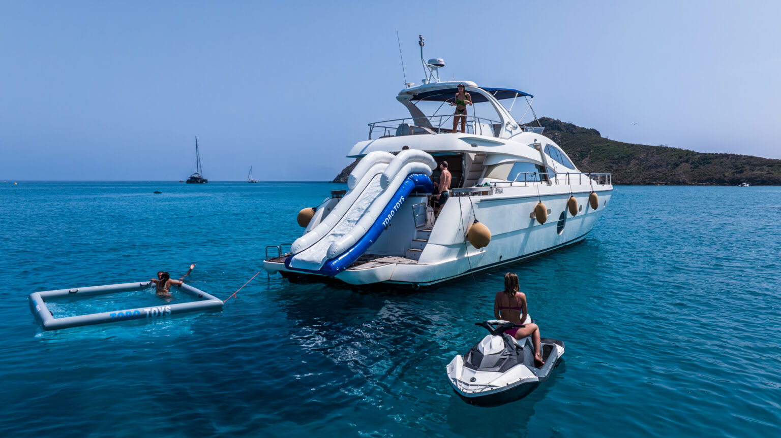 Yacht au mouillage avec un toboggan gonflable Tobo Toys, une piscine flottante et un scooter des mers